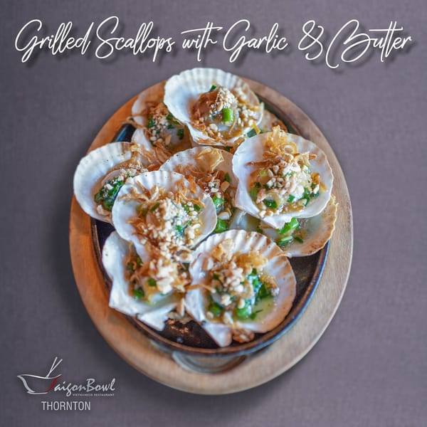 A platter of Vietnamese grilled scallops with garlic, butter, peanuts, and green onions in their shells.
