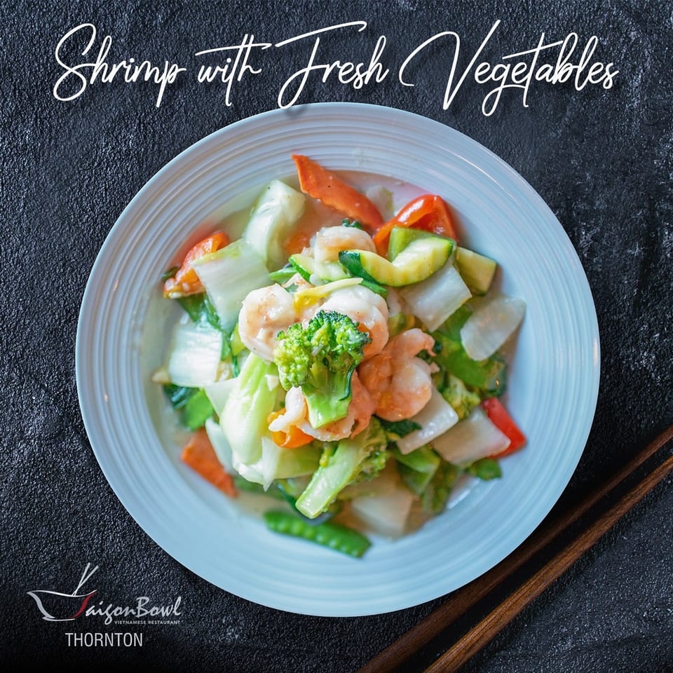 A white bowl of Saigon Bowl's shrimp with fresh vegetables, including broccoli, carrots, and zucchini.