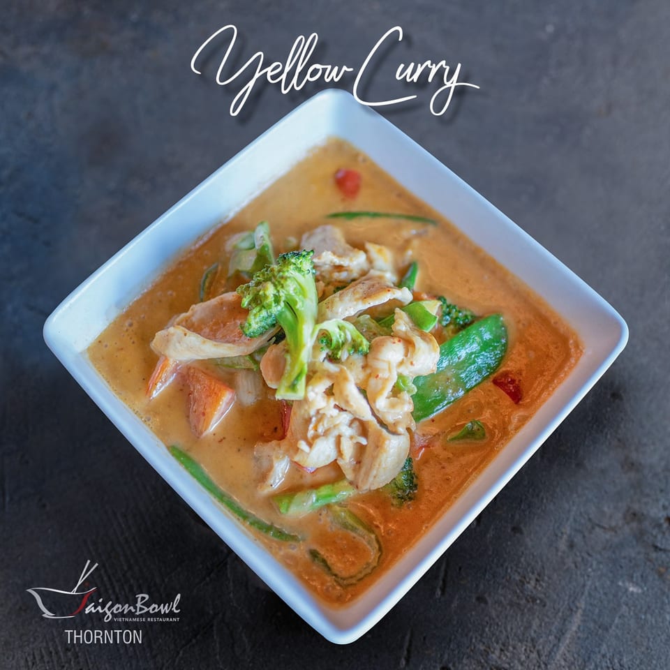 Saigon Bowl's yellow curry with chicken, broccoli, and vegetables in a white square bowl.