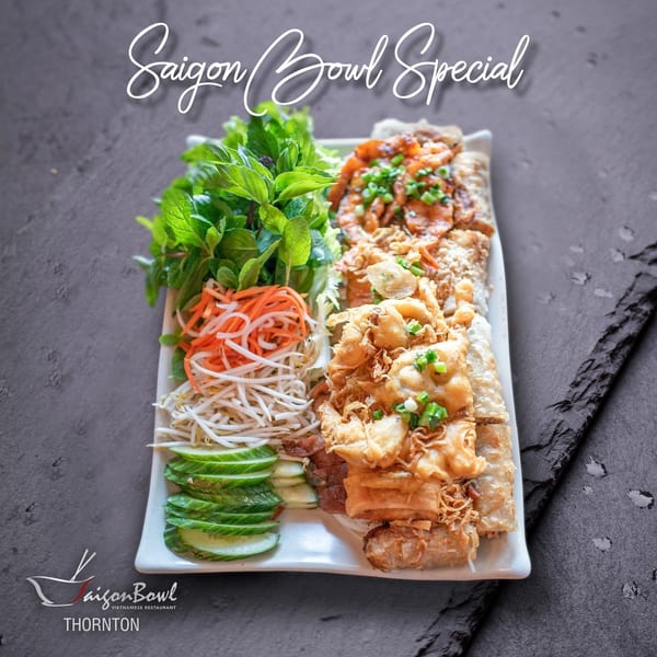 A Saigon Bowl Special platter with spring rolls, shrimp, fresh herbs, bean sprouts, carrots, and cucumber.